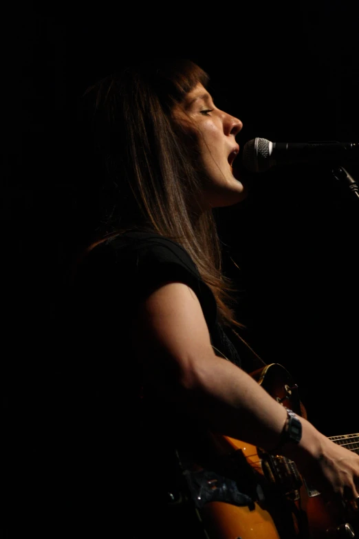 a woman playing an electric guitar in front of a microphone