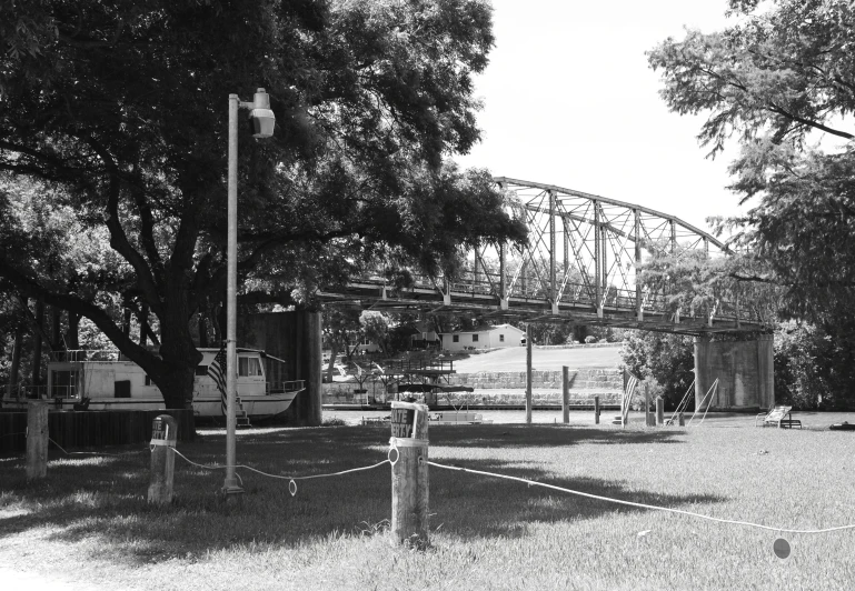 a black and white po shows a tree, gate and train tracks