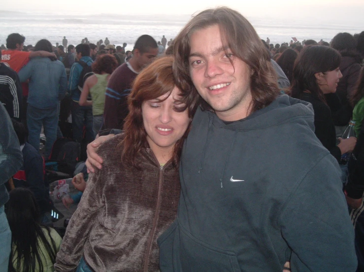 two people hugging each other by the ocean