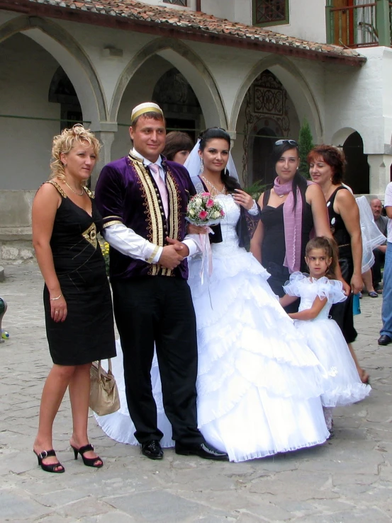 a bride in white dress standing with a bride and groom