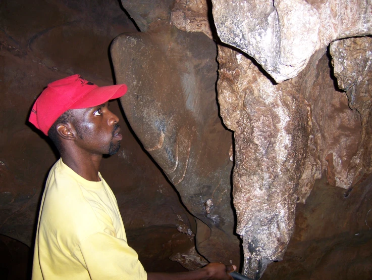 man wearing red hat by rock formation at night