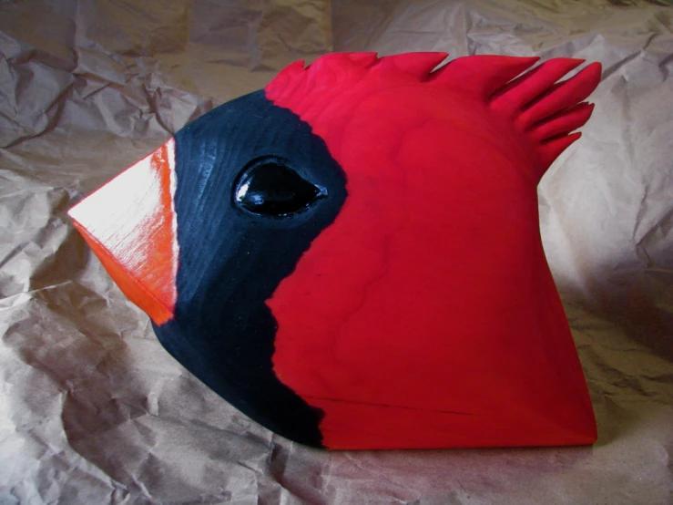 a wooden fish with red, black and orange eyes