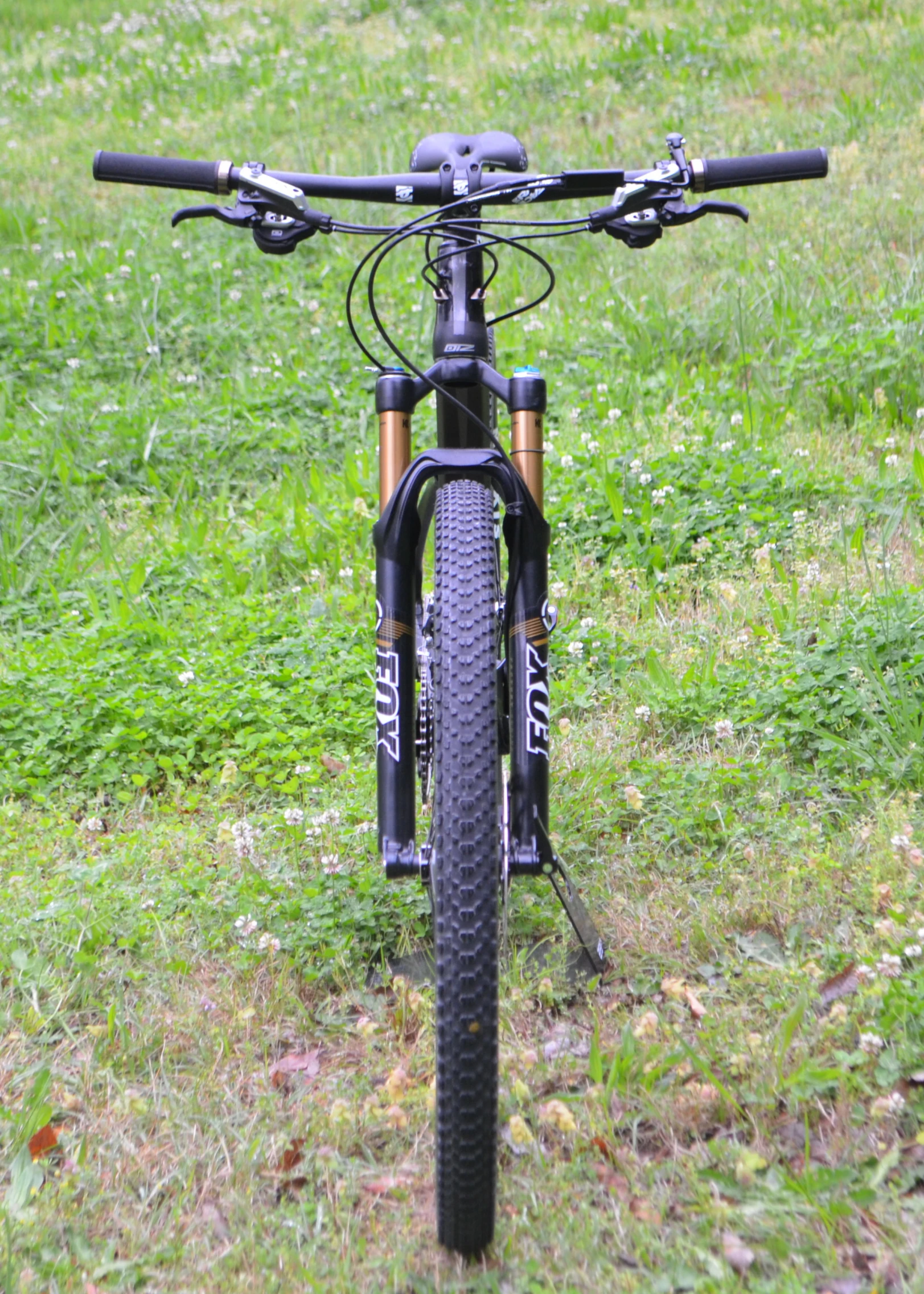 a bike in grass sitting in front of a fence