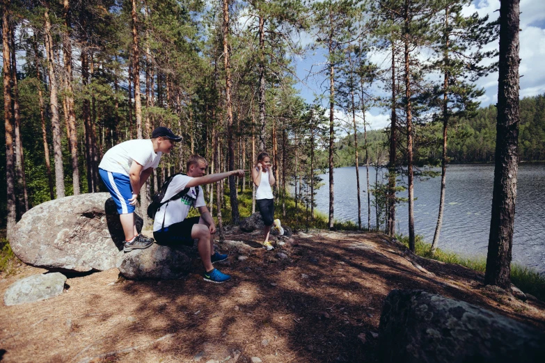 two s on rocks pointing towards a lake