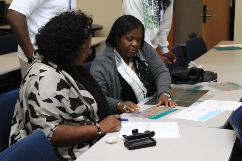 two women are sitting at a table with papers and a calculator