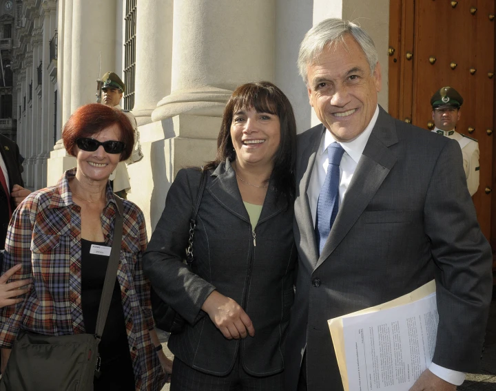 a smiling couple stands beside a man in a suit and tie with an official lady on her right side