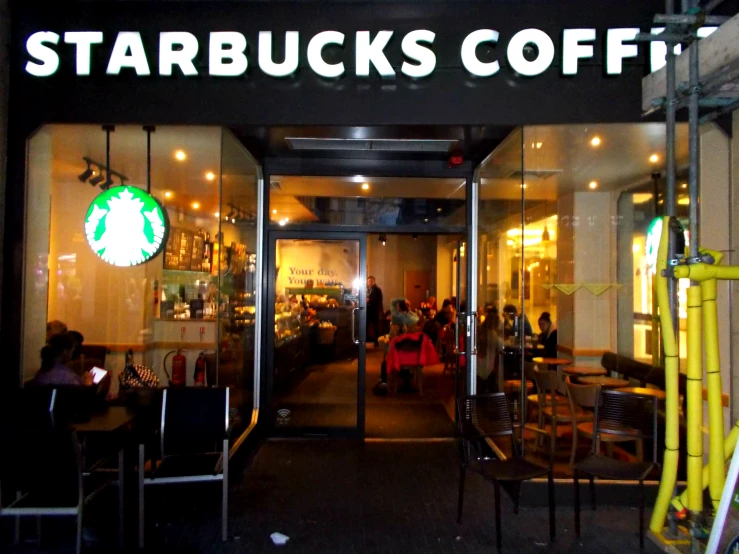 people are outside a starbucks coffee shop at night