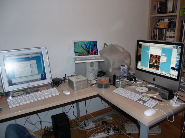 two computers on a desk with books in the background