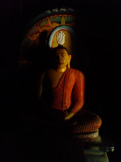 a buddha statue sitting in the dark in a darkened room