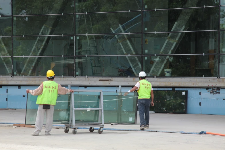 workers wearing neon yellow vests moving construction equipment