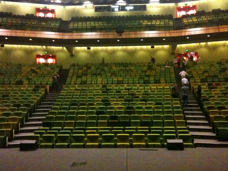people standing inside of a theater with green seats