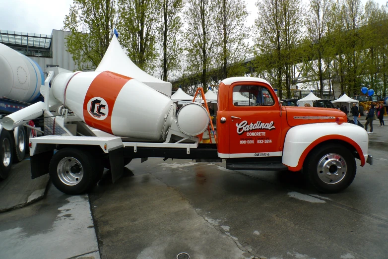 an orange and white truck with a large white cone on it's flatbed