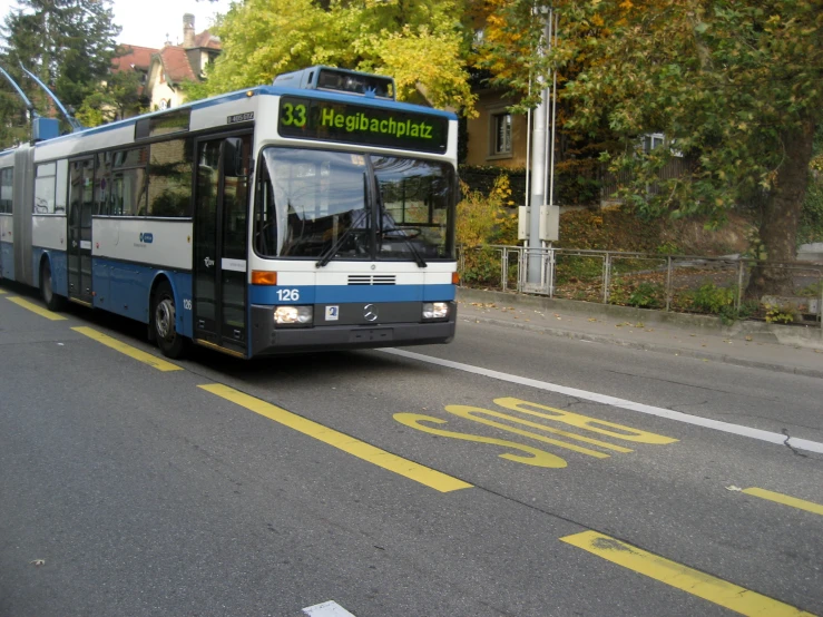 a blue and white bus traveling down a street
