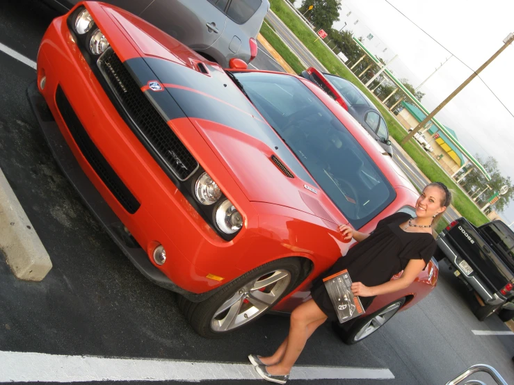 a woman in a dress sitting on top of a red car