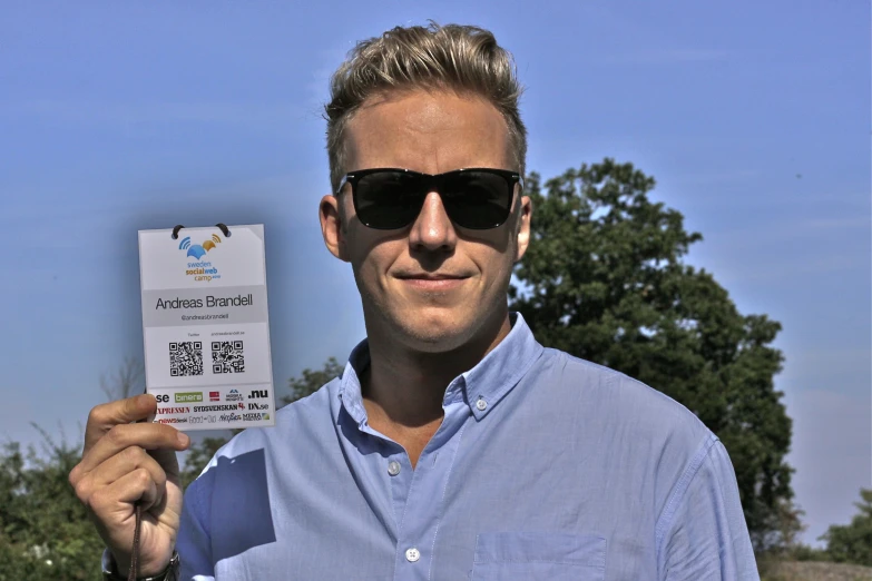 man with sunglasses holding up a ticket for an olympic ceremony