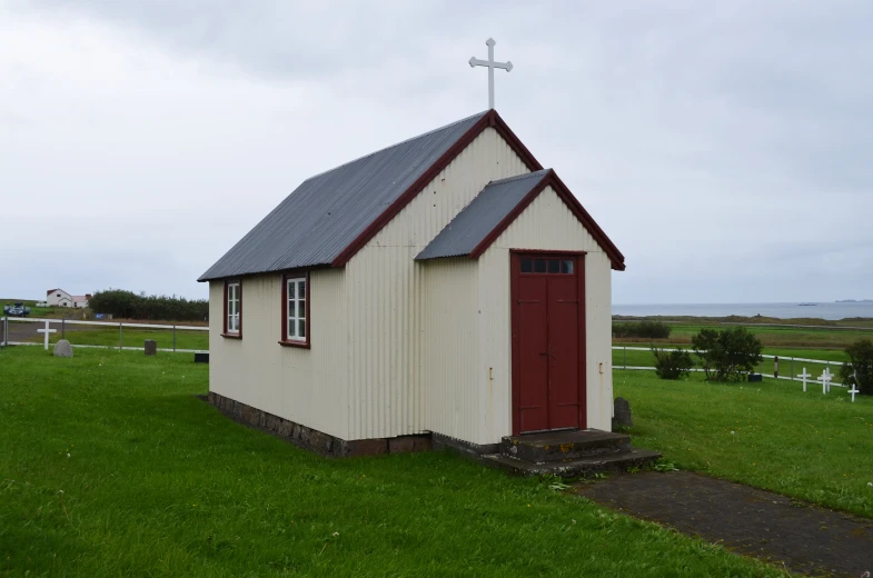 a small church sits in the middle of a green field