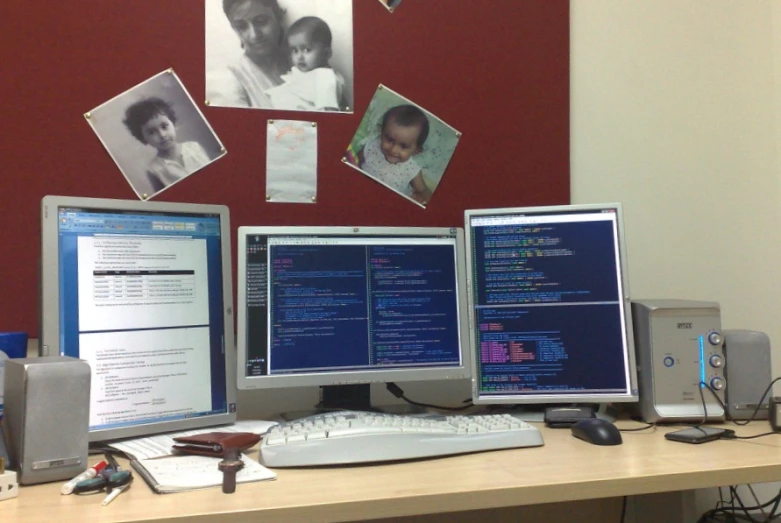 a desk with three computers and multiple screens