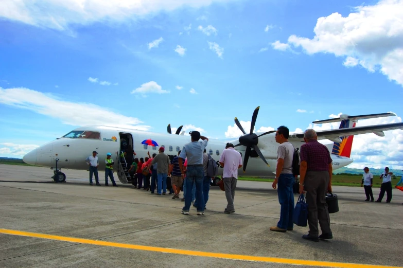 several men stand in line next to the nose of a airplane