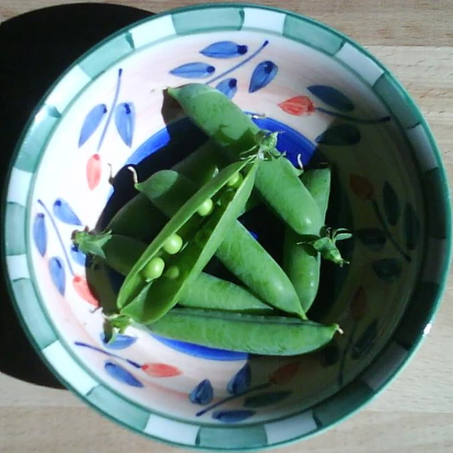 a bowl filled with peas and the pods on it