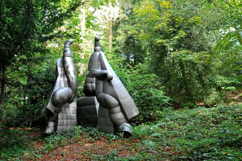 two very large grey, strange sculptures in the woods