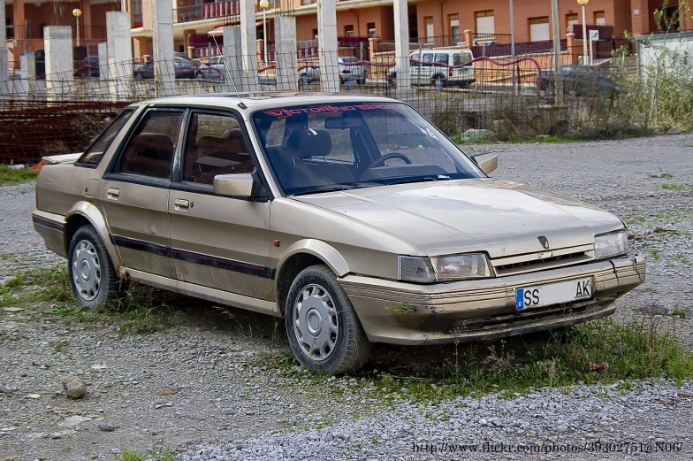 the dirty car is sitting on the gravel