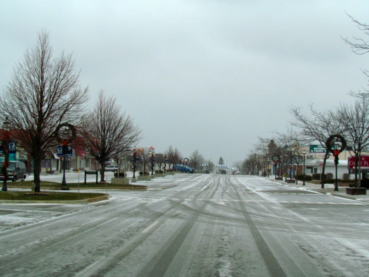 a snow covered street with a few trees and some signs