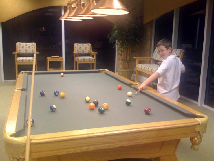 a boy plays pool at his apartment in the day time