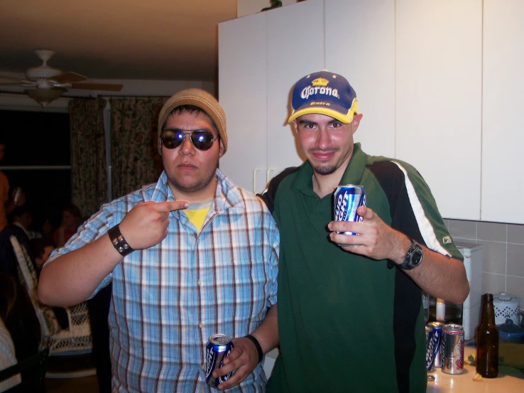 two men wearing hats are holding up beer