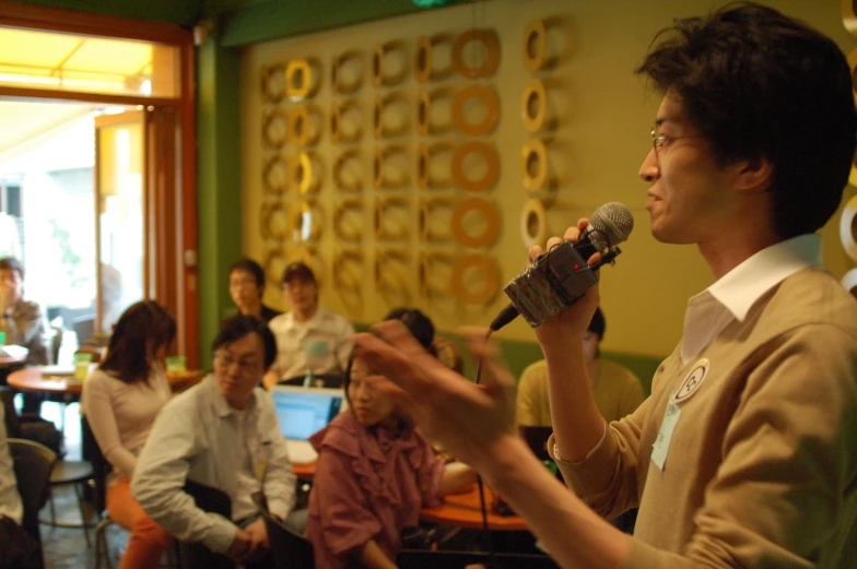 a man holding up a microphone with a group of people behind him