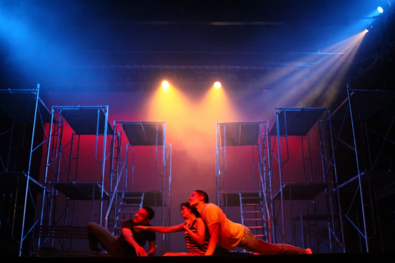 two men in front of a stage light with their hands on each other