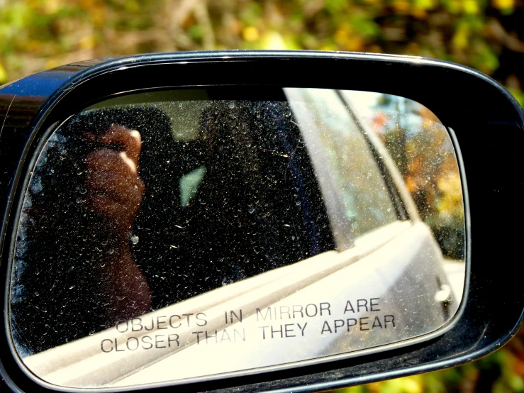 a person reflected in the side view mirror of a car