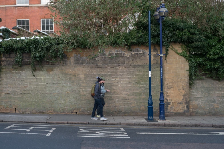 a man on a sidewalk near a brick wall