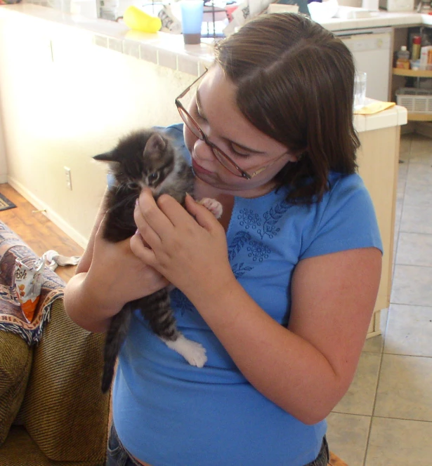 a women who is holding a kitten in her hands