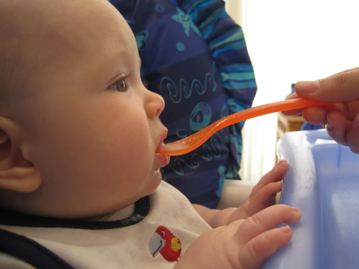 the baby is trying to brush its teeth with an orange brush