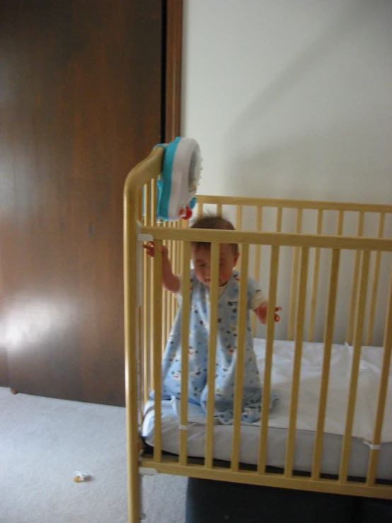 a small child sitting in a crib looking out a doorway