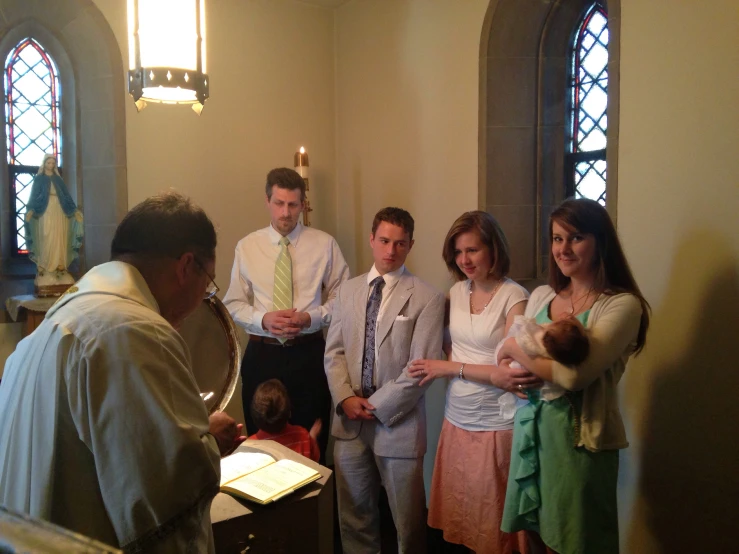 a group of people in a room with one holding a baby