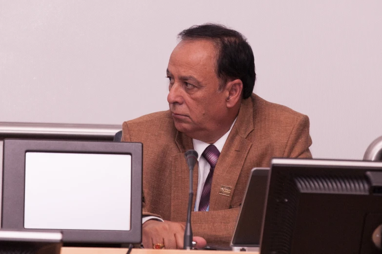 man wearing a suit looking at computer monitor screen