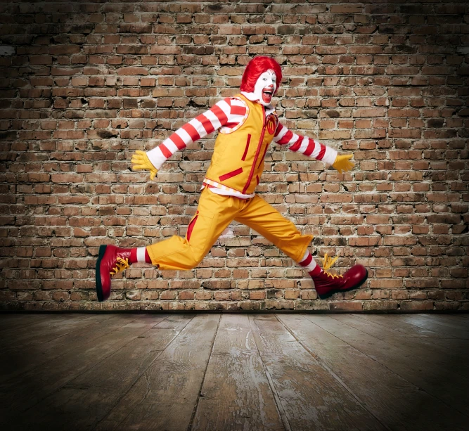 an image of a man dressed as a joker running by a brick wall