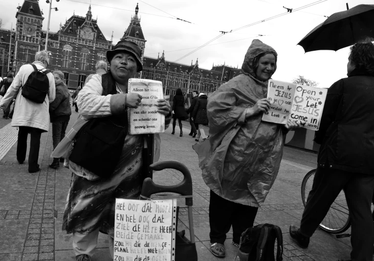 two woman with umbrellas on the street holding signs