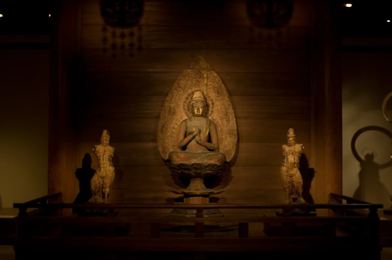 a very elegant wooden display case with statues and a buddha statue