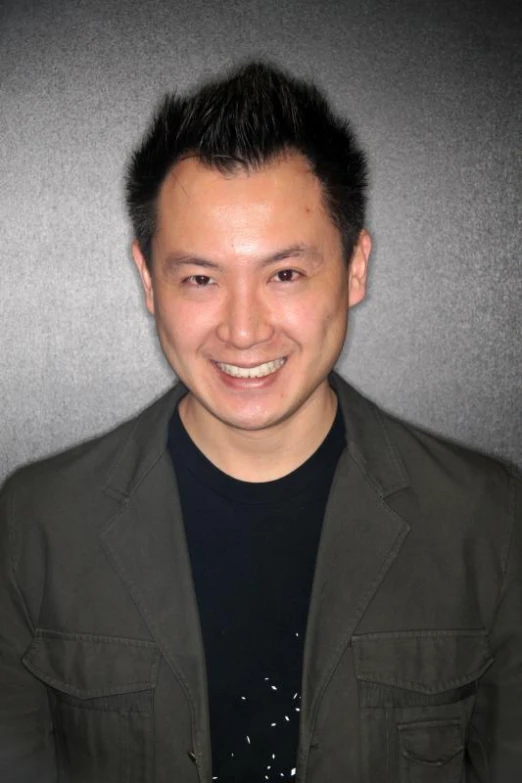 a man with short hair smiling and wearing a green jacket