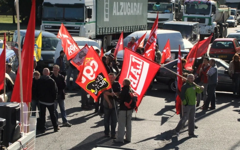 a group of people standing on a city street holding red flags