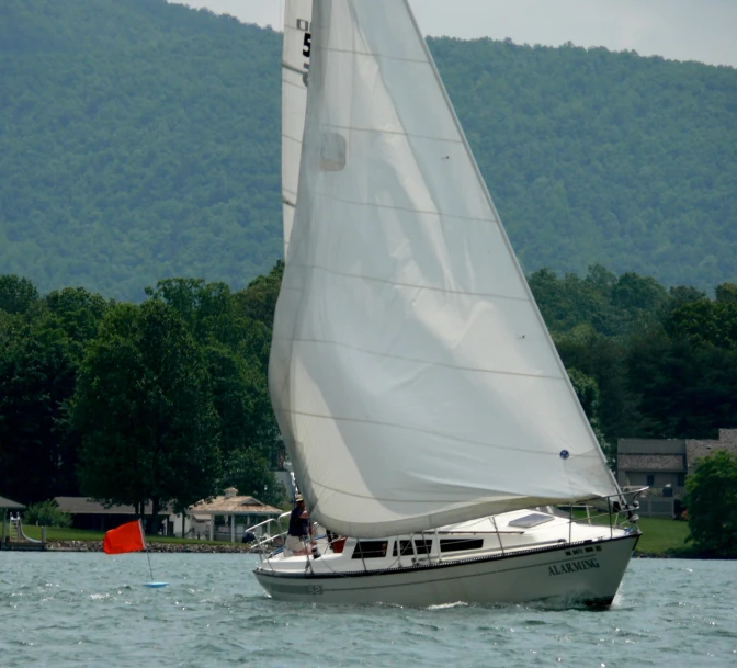 there is a boat with white sails on the water