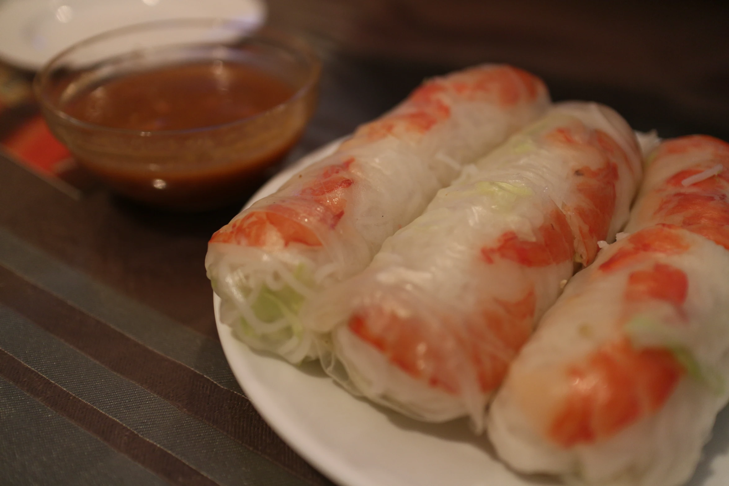 four spring rolls sit on a white plate next to dipping sauce