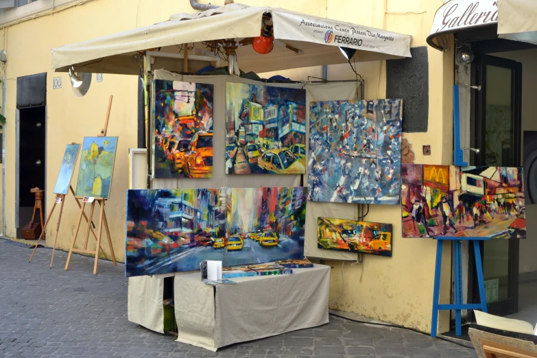 a vendor selling various paintings in a street side marketplace