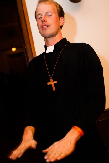 a priest is standing in a room wearing a cross necklace
