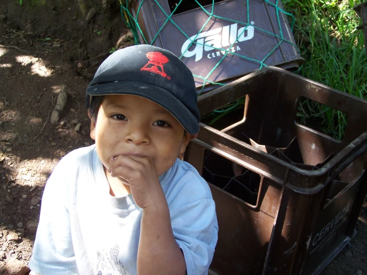 a little boy is sitting next to a garbage can