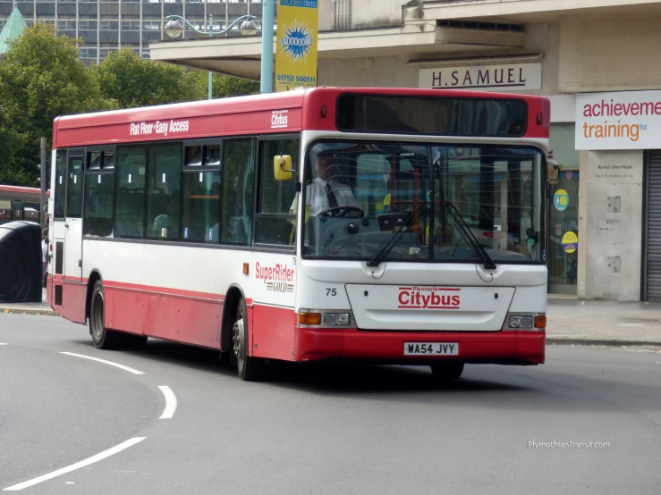 the red and white bus drives down a street