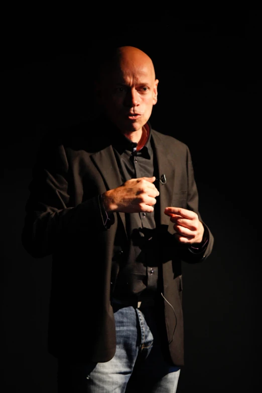 a man standing in the dark with his hands folded