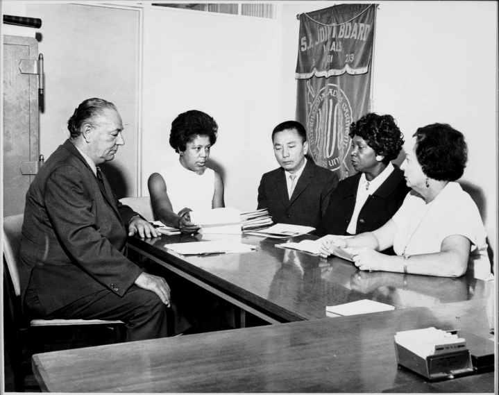 five people sitting around a conference table in a conference room